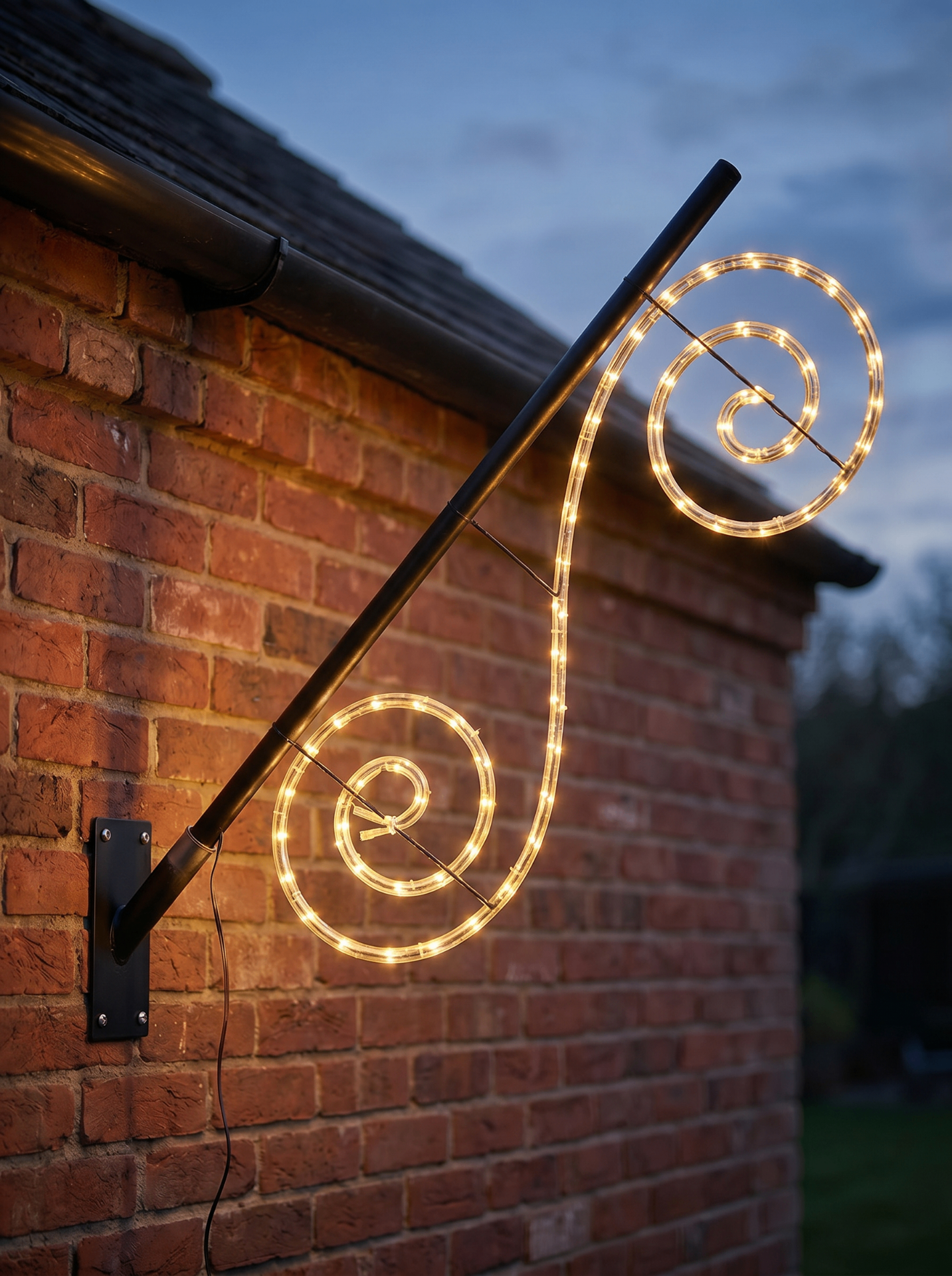 Twinkle Pole Curly Swirl aan een bakstenen gevel in de schemering